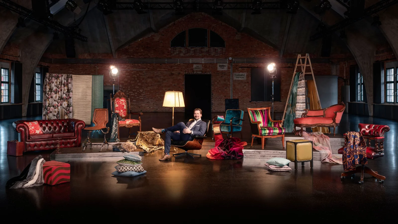 Mann auf einem sessel inmitten von vielen Polstermöbeln