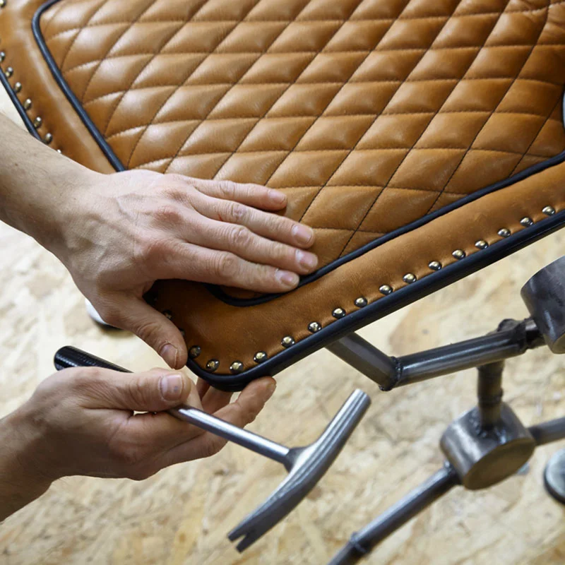 nahaufnahme wie ein handwerker an einem lederstuhl arbeitet